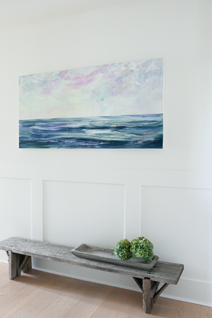 Installed Ocean landscape painting in a modern farmhouse interior with a low weathered wooden bench below.  