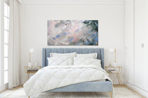 A green and pink modern minimalist painting hangs above a tufted blue upholstered bed.  The bedroom is airy and white, traditional and modern. 